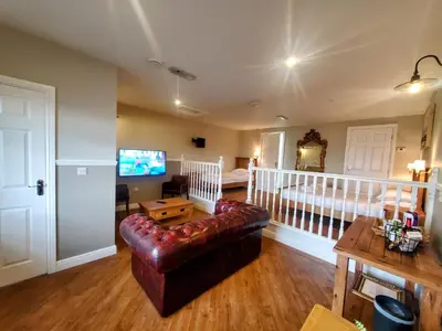 a living room with a leather couch and a bed at The Golden Ball Cottages in Morecambe