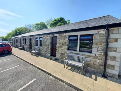 a stone building with two benches in front of it at The Golden Ball Cottages in Morecambe