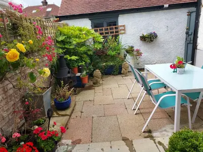 a patio with a table and chairs and flowers at 2 bed apartment 5min from sea in bare Morecombe in Morecambe