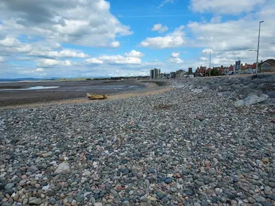 a rocky beach with a bench on the beach at 2 bed apartment 5min from sea in bare Morecombe in Morecambe