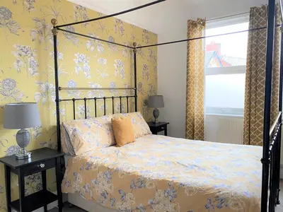 a bedroom with a canopy bed with yellow wallpaper at Victorian Villa close to Liverpool City Centre in Liverpool