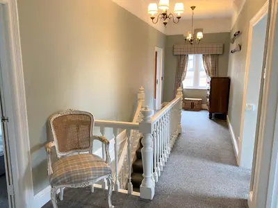 a hallway with a staircase with a chair and a chandelier at Victorian Villa close to Liverpool City Centre in Liverpool