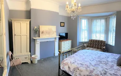 a bedroom with a bed and a television and a chandelier at Victorian Villa close to Liverpool City Centre in Liverpool