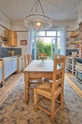 a kitchen with a wooden table with chairs and a chandelier at Victorian Villa close to Liverpool City Centre in Liverpool