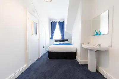 a white bedroom with a bed and a sink at The Adonis Hotel in Blackpool
