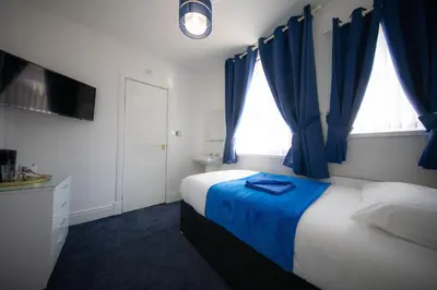 a bedroom with a bed with blue drapes at The Adonis Hotel in Blackpool