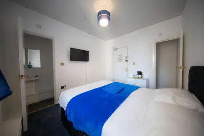a bedroom with a large white bed with a blue blanket at The Adonis Hotel in Blackpool