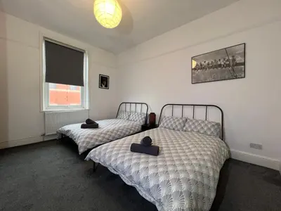 a bedroom with two beds and a window at Peaky blinders apartment 5 min walk to Blackpool tower sleeps up to 14 in Blackpool