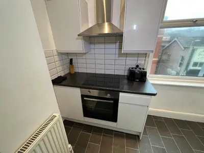 a kitchen with white cabinets and a stove top oven at Peaky blinders apartment 5 min walk to Blackpool tower sleeps up to 14 in Blackpool