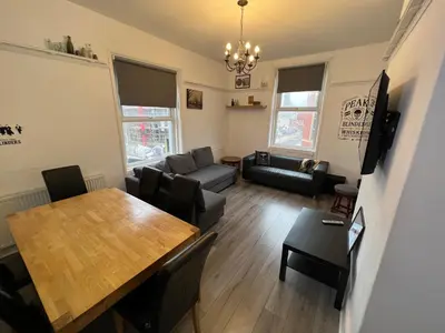 a living room with a table and a couch at Peaky blinders apartment 5 min walk to Blackpool tower sleeps up to 14 in Blackpool