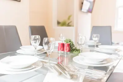 a dining room table with white plates and wine glasses at *KING BED* LUXURY CITY CENTRE HOUSE in Barrow in Furness