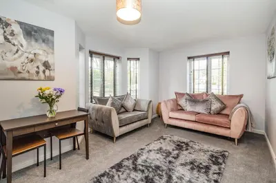 a living room with two couches and a table at Mayfair in Wigan
