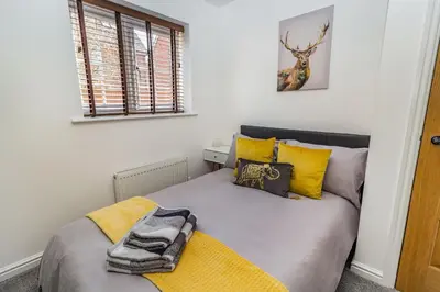 a bedroom with a bed with yellow pillows at Mayfair in Wigan