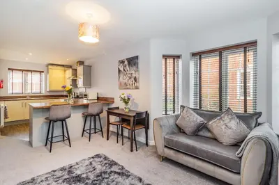 a living room with a couch and a kitchen at Mayfair in Wigan