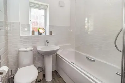 a white bathroom with a toilet and a sink and a tub at Mayfair in Wigan
