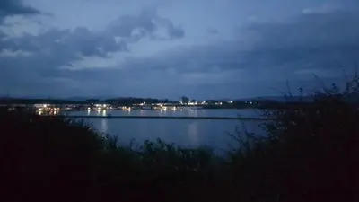a view of a lake at night with lights at Herdwicks in Millom