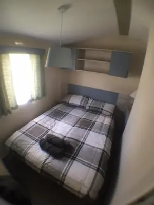 a small bedroom with a bed with a plaid blanket at Driftwood Cottage Port Haverigg Marina Village in Millom