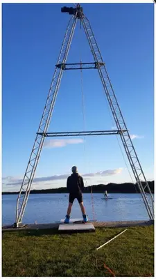a man is on a swing in front of the water at Driftwood Cottage Port Haverigg Marina Village in Millom