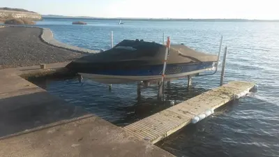 a boat sitting on the water next to a dock at Driftwood Cottage Port Haverigg Marina Village in Millom