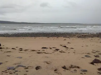 a beach with rocks and the ocean on a cloudy day at Driftwood Cottage Port Haverigg Marina Village in Millom