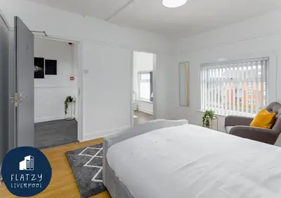 a white bedroom with a bed and a living room at FLATZY - 6 bed Oasis Close to Football Stadiums in Liverpool
