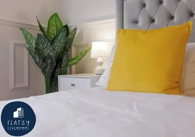a bedroom with a white bed with a yellow pillow at FLATZY - 6 bed Oasis Close to Football Stadiums in Liverpool