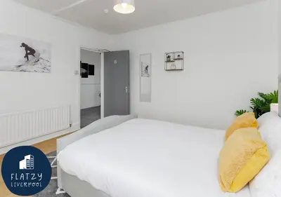 a bedroom with a large white bed with yellow pillows at FLATZY - 6 bed Oasis Close to Football Stadiums in Liverpool