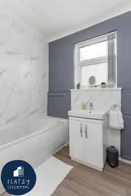 a bathroom with a white tub and a sink at FLATZY - 6 bed Oasis Close to Football Stadiums in Liverpool