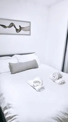 a white bed with two towels on top of it at Ivy Chic Apartments by CityNest in Blackpool
