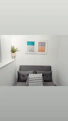 a bed in a white room with two pictures on the wall at Ivy Chic Apartments by CityNest in Blackpool