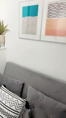 a couch with two pillows and two pictures on a wall at Ivy Chic Apartments by CityNest in Blackpool