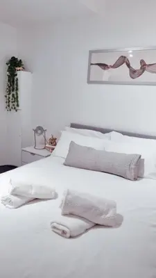 a white bed with white sheets and towels on it at Ivy Chic Apartments by CityNest in Blackpool