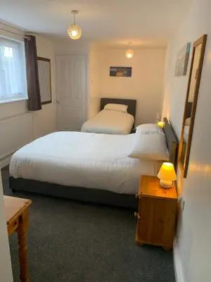 a bedroom with two beds and a table with a lamp at Delamere ground floor holiday flat in Blackpool