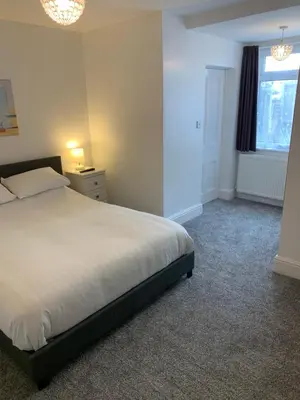 a bedroom with a white bed and a window at Delamere ground floor holiday flat in Blackpool