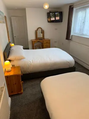 a bedroom with two beds and a table and a window at Delamere ground floor holiday flat in Blackpool