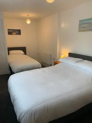 two beds in a hotel room with white sheets at Delamere ground floor holiday flat in Blackpool
