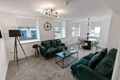 a living room with two green couches and a table at Mode Apartments Winter Gardens Blackpool in Blackpool