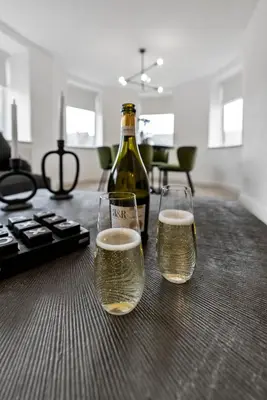 two glasses of beer sitting on a table with a bottle at Mode Apartments Winter Gardens Blackpool in Blackpool