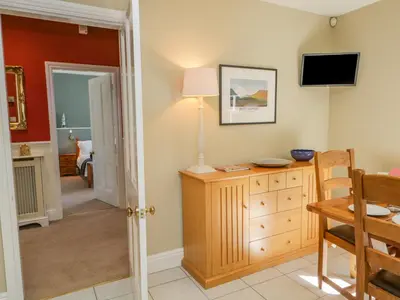 a living room with a table and a tv on the wall at Crow's Nest in Carnforth