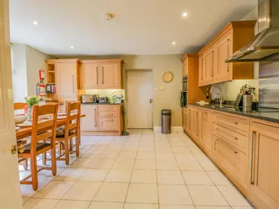 a kitchen with wooden cabinets and a table and chairs at Crow's Nest in Carnforth
