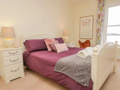 a bedroom with a bed with purple sheets and a window at Crow's Nest in Carnforth