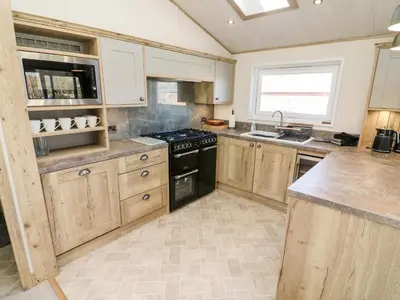 a kitchen with wooden cabinets and a black stove top oven at Curlew Lodge in Carnforth