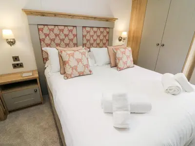 a bedroom with a large white bed with towels on it at Curlew Lodge in Carnforth