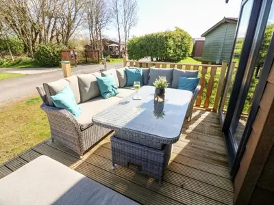 a patio with a couch and a table on a deck at Curlew Lodge in Carnforth