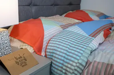 a bed with a comforter and a sign on a table at TCO Luxury House in Liverpool