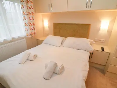 a bedroom with a white bed with two slippers on it at The Bobbin, Number 11 in Carnforth