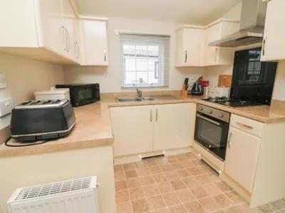 a kitchen with white cabinets and a sink at The Bobbin, Number 11 in Carnforth