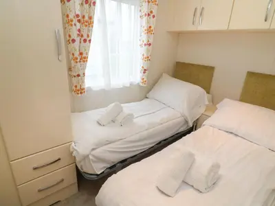 two twin beds in a small room with a window at The Bobbin, Number 11 in Carnforth