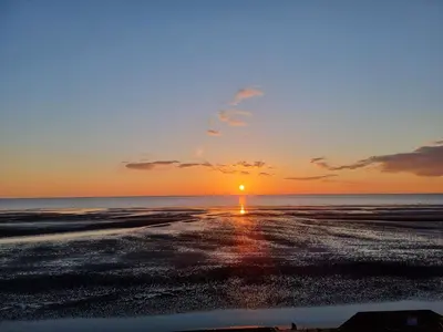 a sunset on the beach with the sun in the horizon at Granada Apartments Derby Road in Blackpool