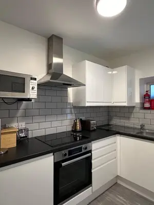 a kitchen with white cabinets and black counter tops at Granada Apartments Derby Road in Blackpool